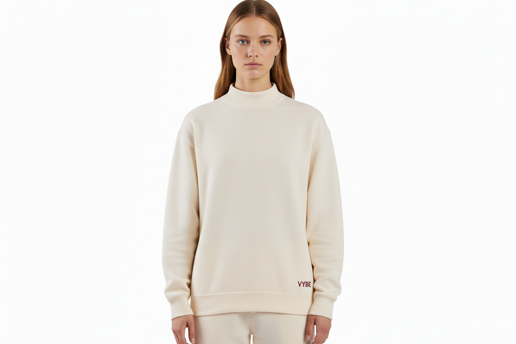 Upper body crop of cream VYBE sweatshirt on female model